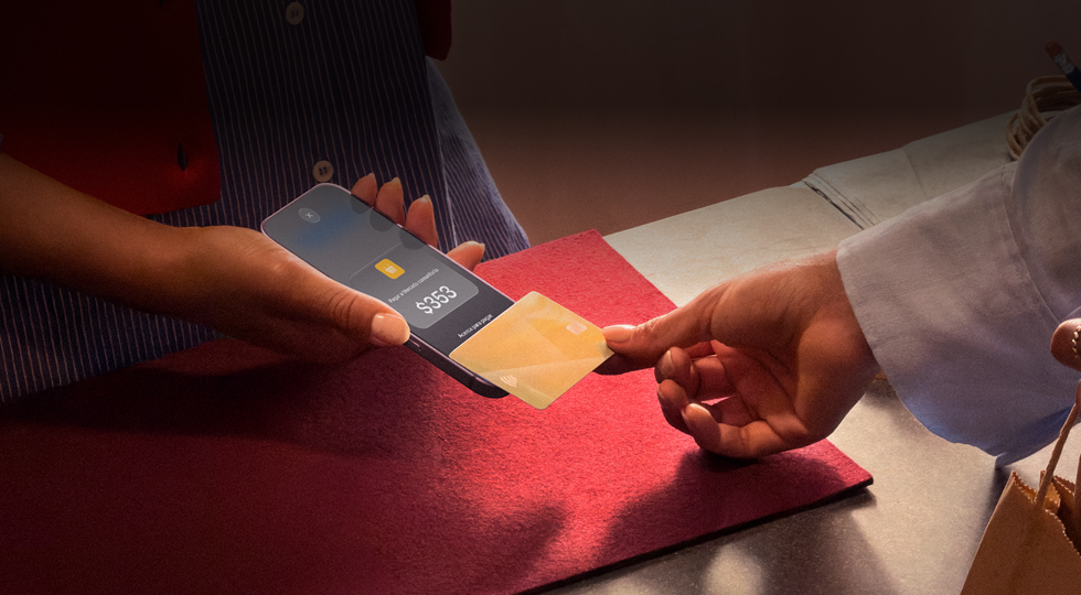 Una mano acerca una tarjeta de crédito a un iPhone para hacer un pago