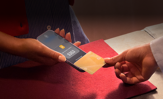 Una mano acerca una tarjeta de crédito a un iPhone para hacer un pago