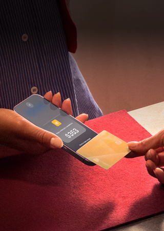Una mano acerca una tarjeta de crédito a un iPhone para hacer un pago